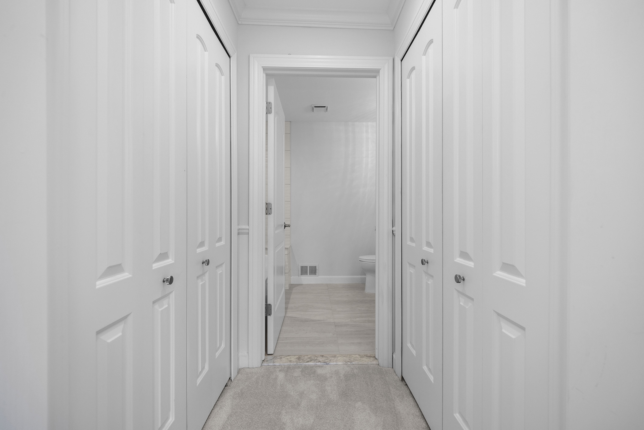 A beautifully finished mudroom with white cabinets and gray flooring.